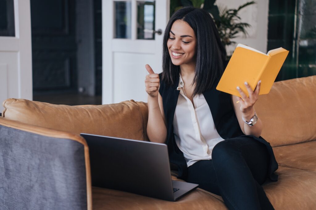 Brazilian young woman at business meet via internet using video call by laptop, sitting on sofa